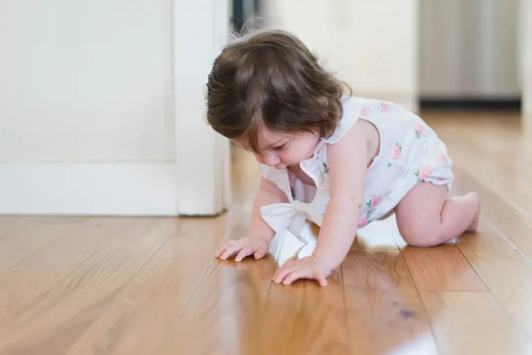 Jeune enfant jouant à quatre pattes sur le parquet