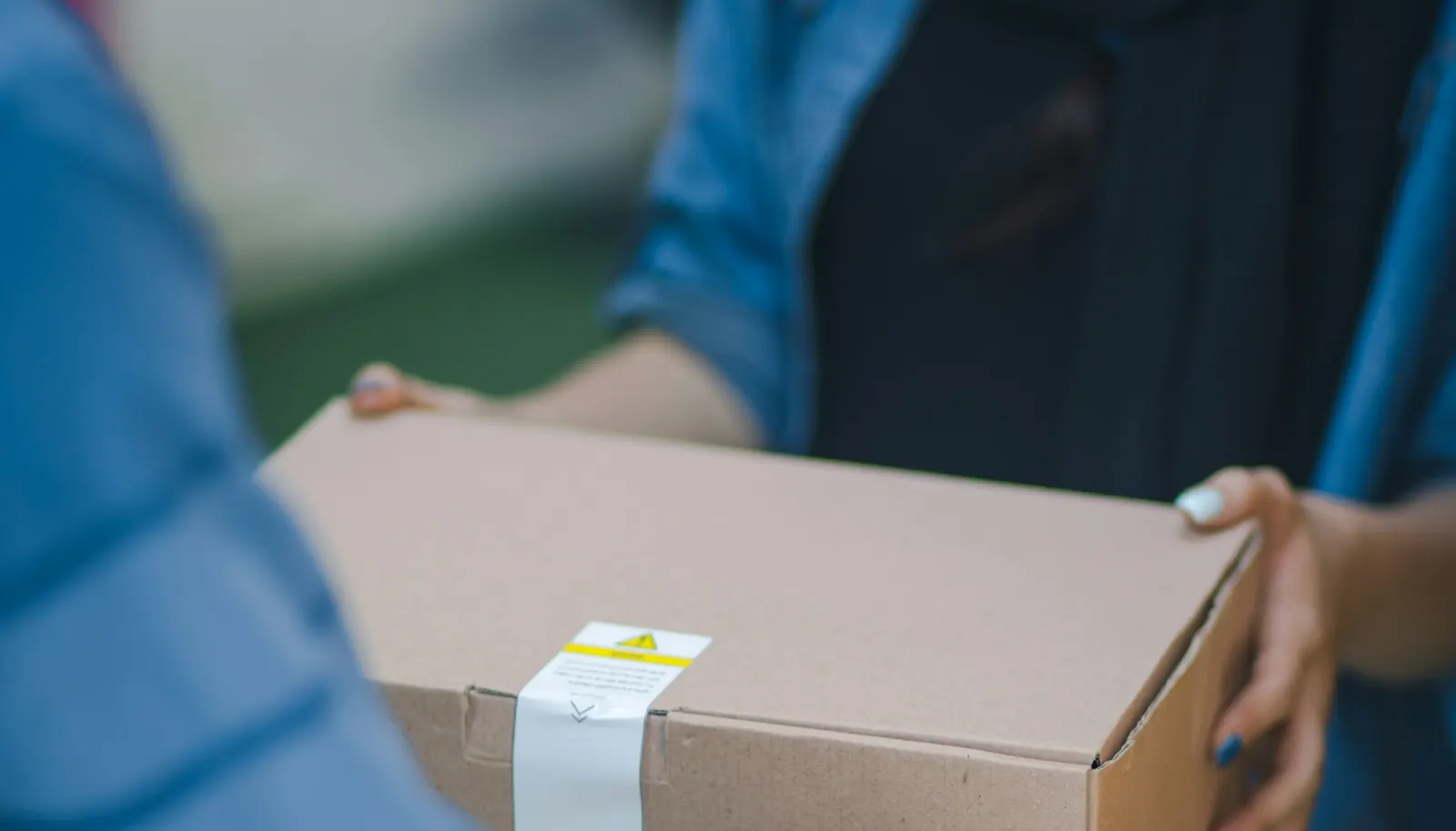 Livreur remettant un colis en carton en main propre à son destinataire