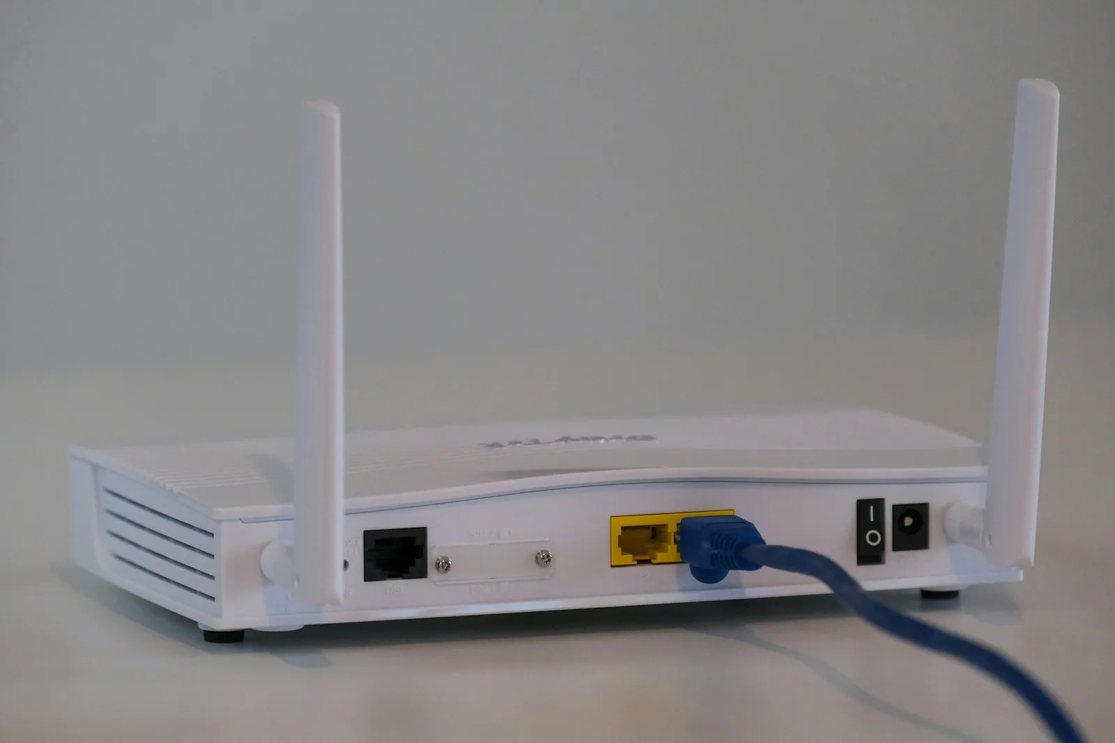 Routeur Wi-Fi blanc vu de dos avec ses câbles